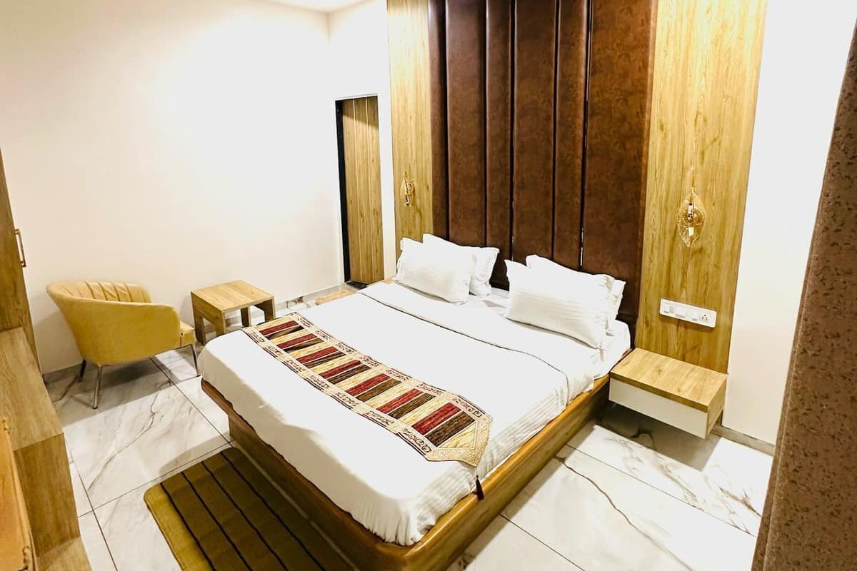 A modern bedroom with a large bed, wooden headboard, marble flooring, and a ceiling fan.