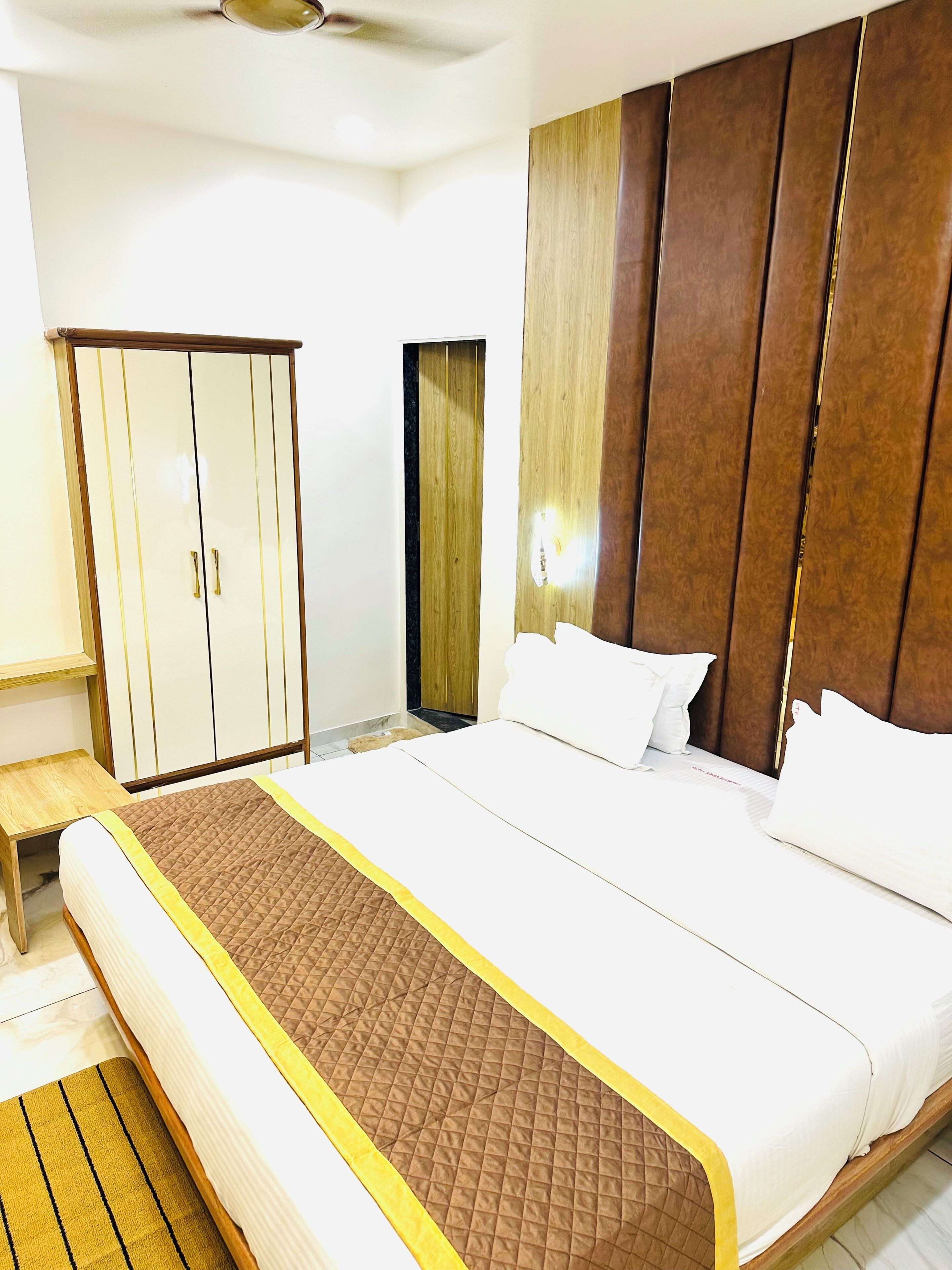 A hotel room with a large bed, a wardrobe, and a mirror.