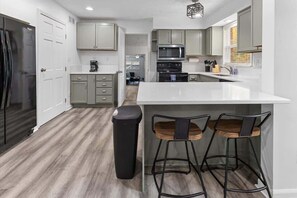 A modern kitchen with a white countertop, stainless steel appliances, and grey cabinetry.