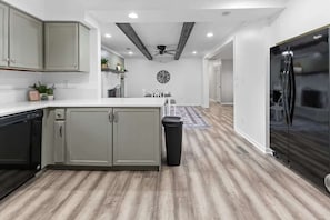 A modern kitchen with a central island, a black refrigerator, and a ceiling fan.
