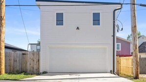 A single-story house with a garage, a wooden fence, and utility poles. - Cityview Cottage (Indianapolis)