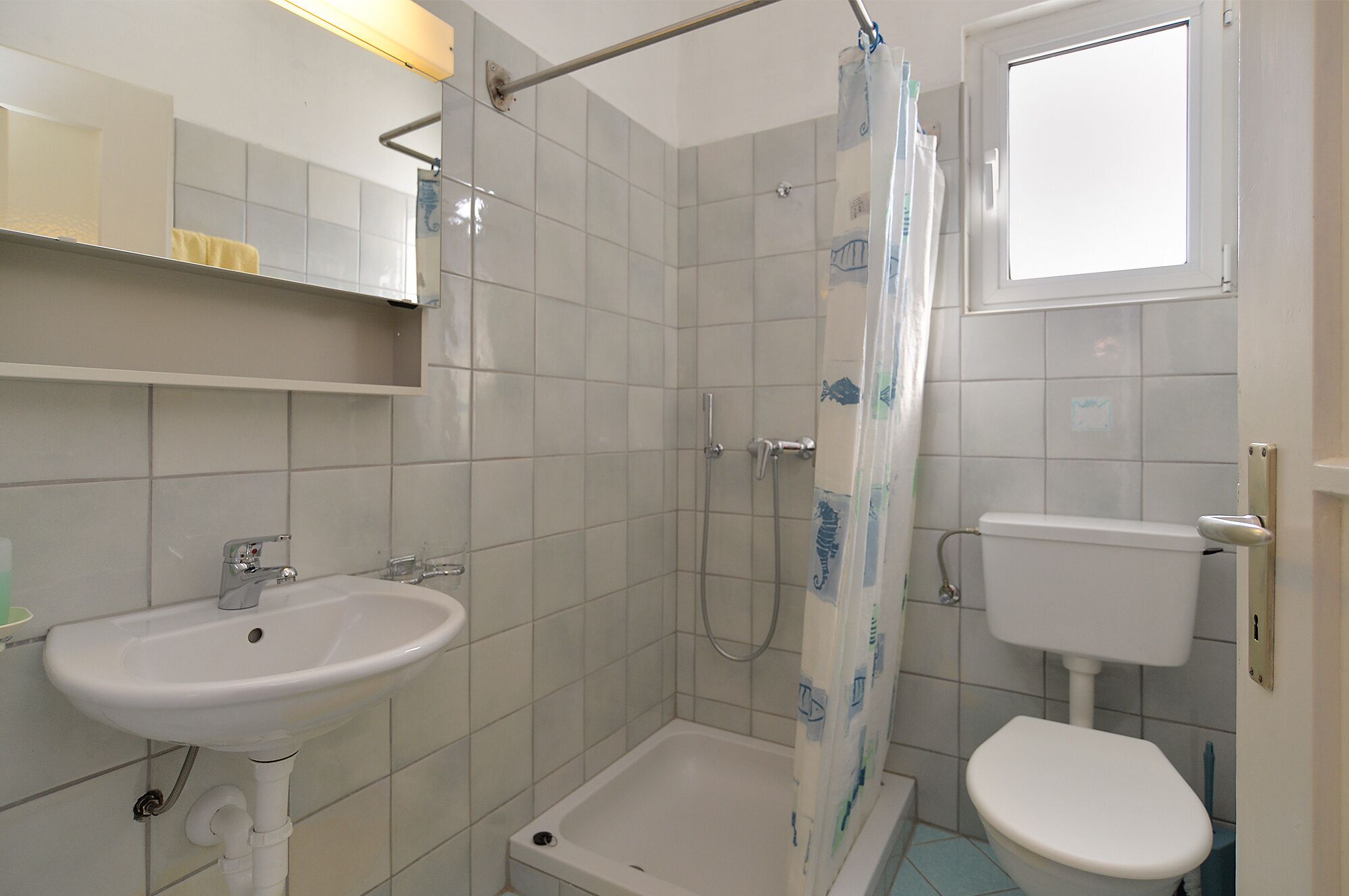 Ein Badezimmer mit Waschbecken, Toilette, Dusche und einem Fenster.