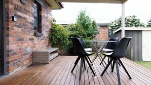A wooden deck with a brick wall, a glass table, and four black chairs. - Spacious 3-Bed, Mins from City Centre (Newstead)