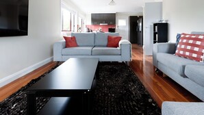 A modern living room with a grey sofa, a black coffee table, and a red and white checkered pillow. - Spacious 3-Bed, Mins from City Centre (Newstead)