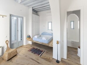 A room with a bed, a small window, a door, and a floor lamp. - Villa With Panoramic sea Views (Mykonos)