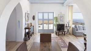 A spacious living room with a large arched doorway leading to a balcony with a beach view.