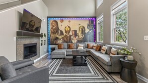 A modern living room with a sectional sofa, a fireplace, and a Star Wars-themed wall mural. - Spacious Town Home near ICC (Indianapolis)