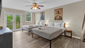 A hotel room with two beds, a ceiling fan, a painting, and a view of greenery through the sliding doors. - Spacious Town Home near ICC (Indianapolis)