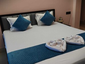 A neatly made bed with a blue quilt, two pillows, and two towels on a blue bedspread. - Dui Kanya Henshel Ghar (Bolpur)