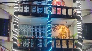 Een meerlaags gebouw met balkons, decoratieve hekwerken en een centraal verlichte sculptuur.