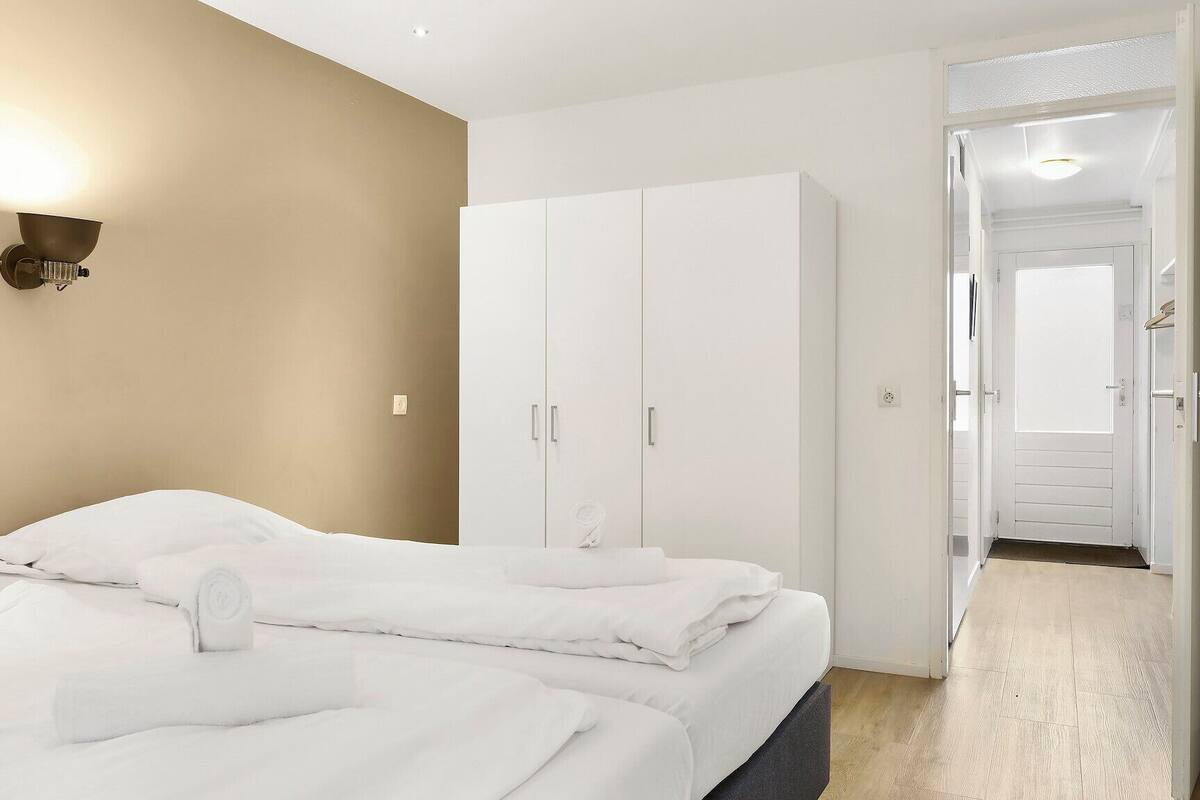 Une chambre d’hôtel avec deux lits, une armoire et une salle de bain visible à travers une porte ouverte.