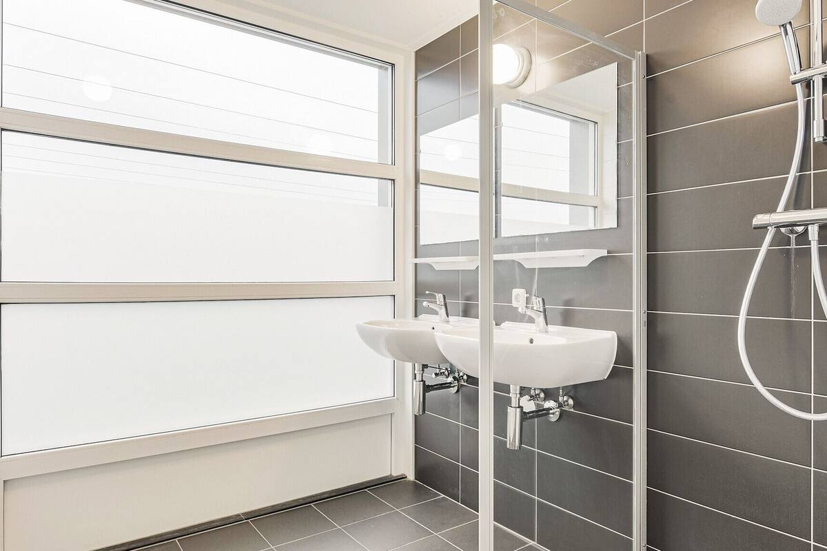 Une salle de bain moderne avec une grande fenêtre, une douche et un lavabo.