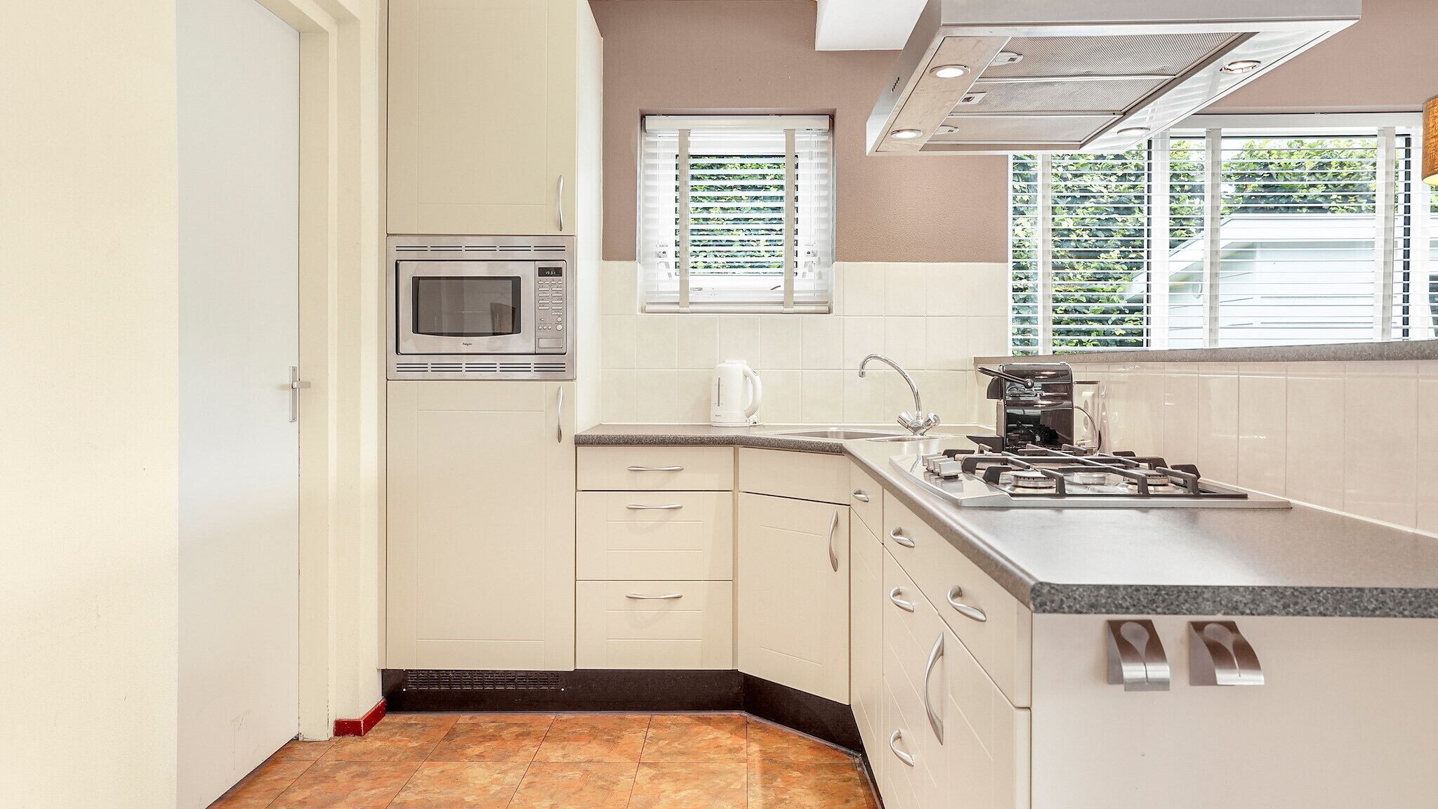 Una cocina compacta equipada con microondas, hervidor y cocina a gas.