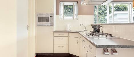 Una cocina compacta equipada con microondas, hervidor y cocina a gas.