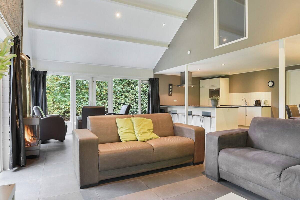 Un salon moderne avec un canapé, une table basse et une cheminée. Il y a également un coin cuisine avec une table à manger et des chaises.