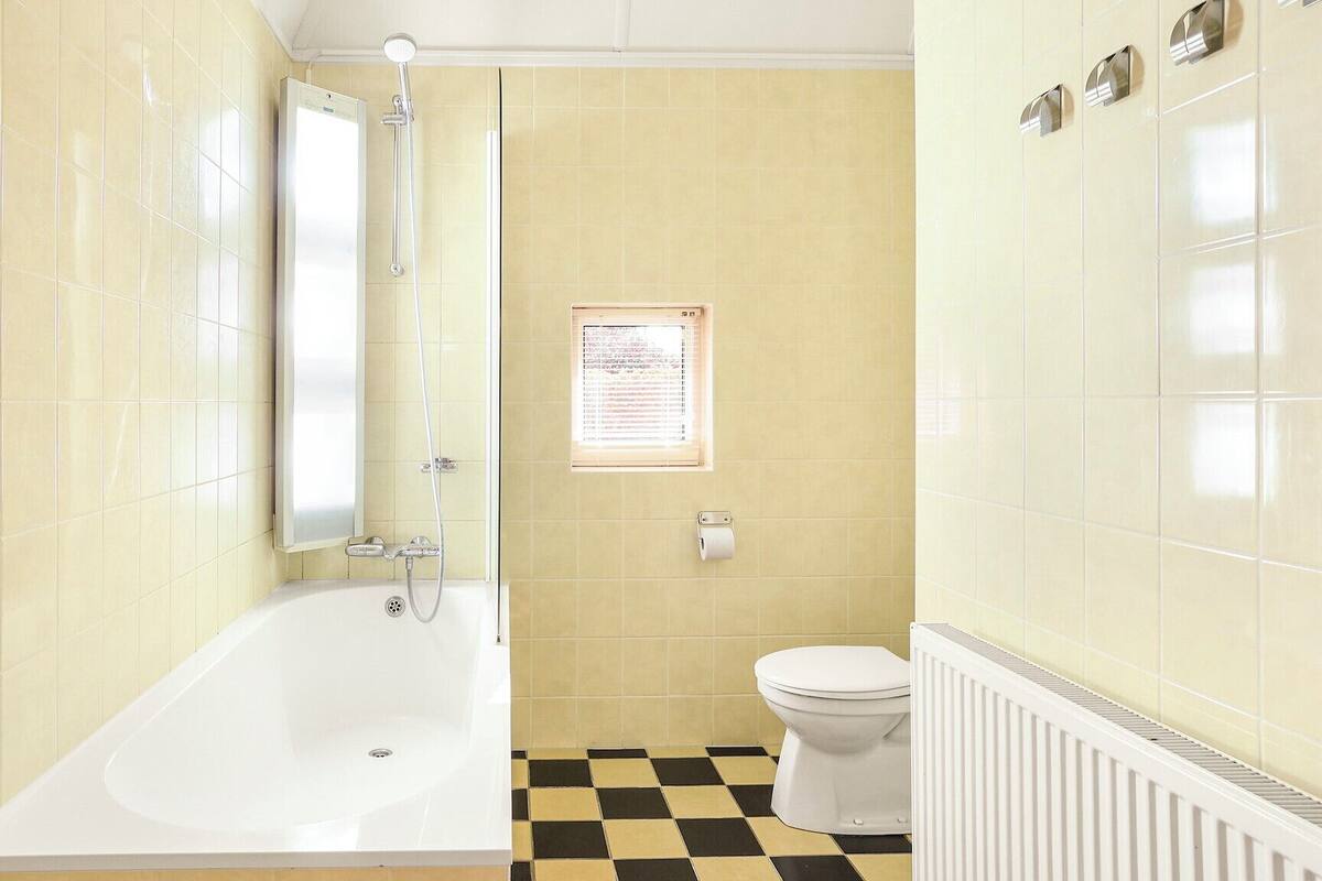 Une salle de bain avec une baignoire, des toilettes et une fenêtre sur laquelle est affiché un avis.