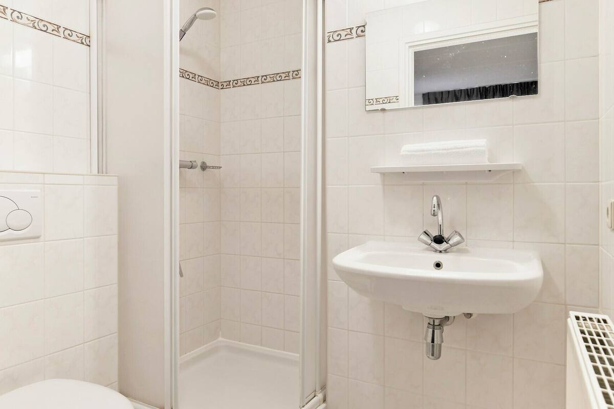 Une salle de bain équipée d’une douche, de toilettes, d’un lavabo et d’une fenêtre située au-dessus du lavabo.