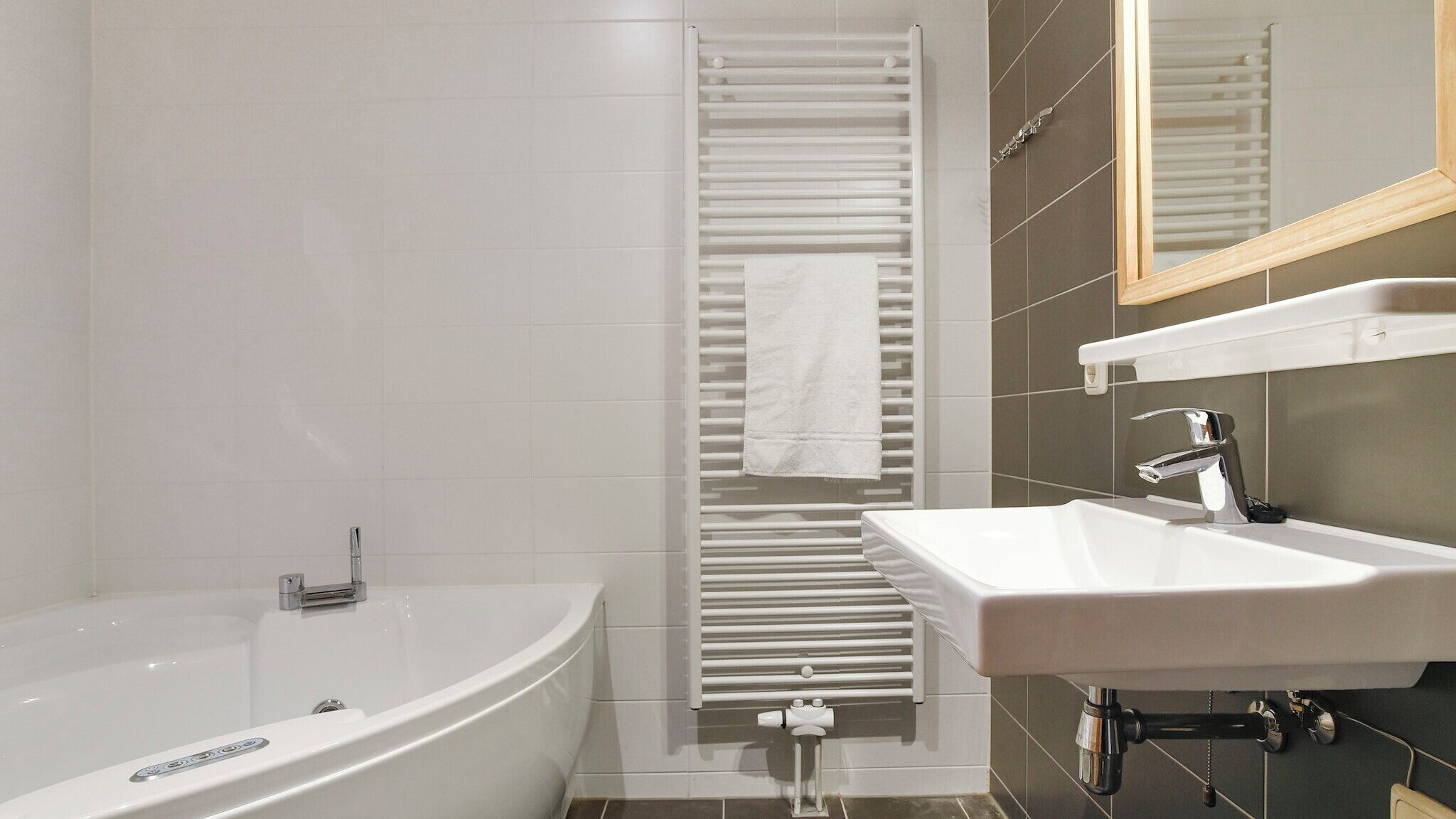 A modern bathroom with a freestanding bathtub, a white sink, and a towel rack.