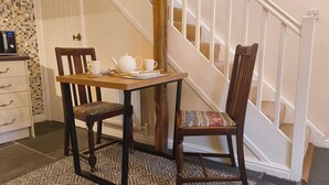 A dining area with a wooden table and chairs, a white teapot, and a cup set. - Cosy Cottage for two in the Centre of Sedbergh (Sedbergh)
