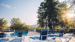 Un área junto a la piscina con sillones de descanso y una terraza de madera.