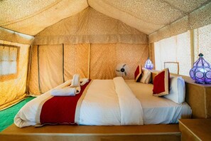 A tent-style room with a bed, a fan, and a decorative lamp.