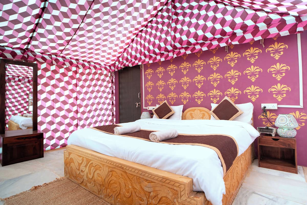 A bedroom with a checkered canopy, a bed with pillows, a nightstand, and a mirror.