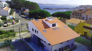Uma cidade costeira com um edifício branco imponente, telhado em azulejos e várias janelas.