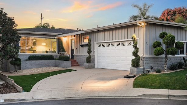 A two-story house with a garage, a well-maintained lawn, and a driveway leading to the front door.