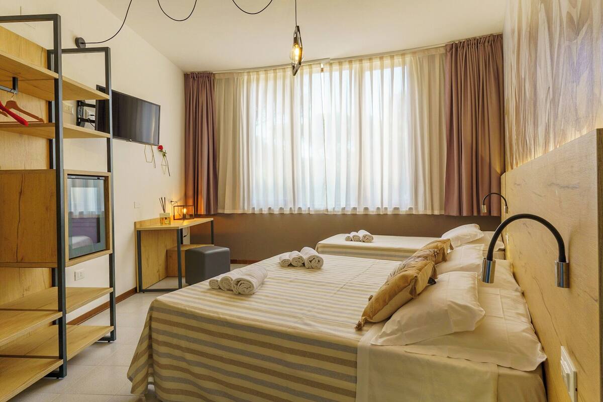 A hotel room with two beds, a desk, a TV, and a wardrobe.