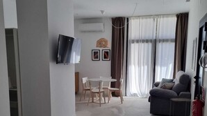 Ett modernt hotellrum med en säng, en tv som är monterad på väggen, en matplats med ett bord och stolar samt en soffa.