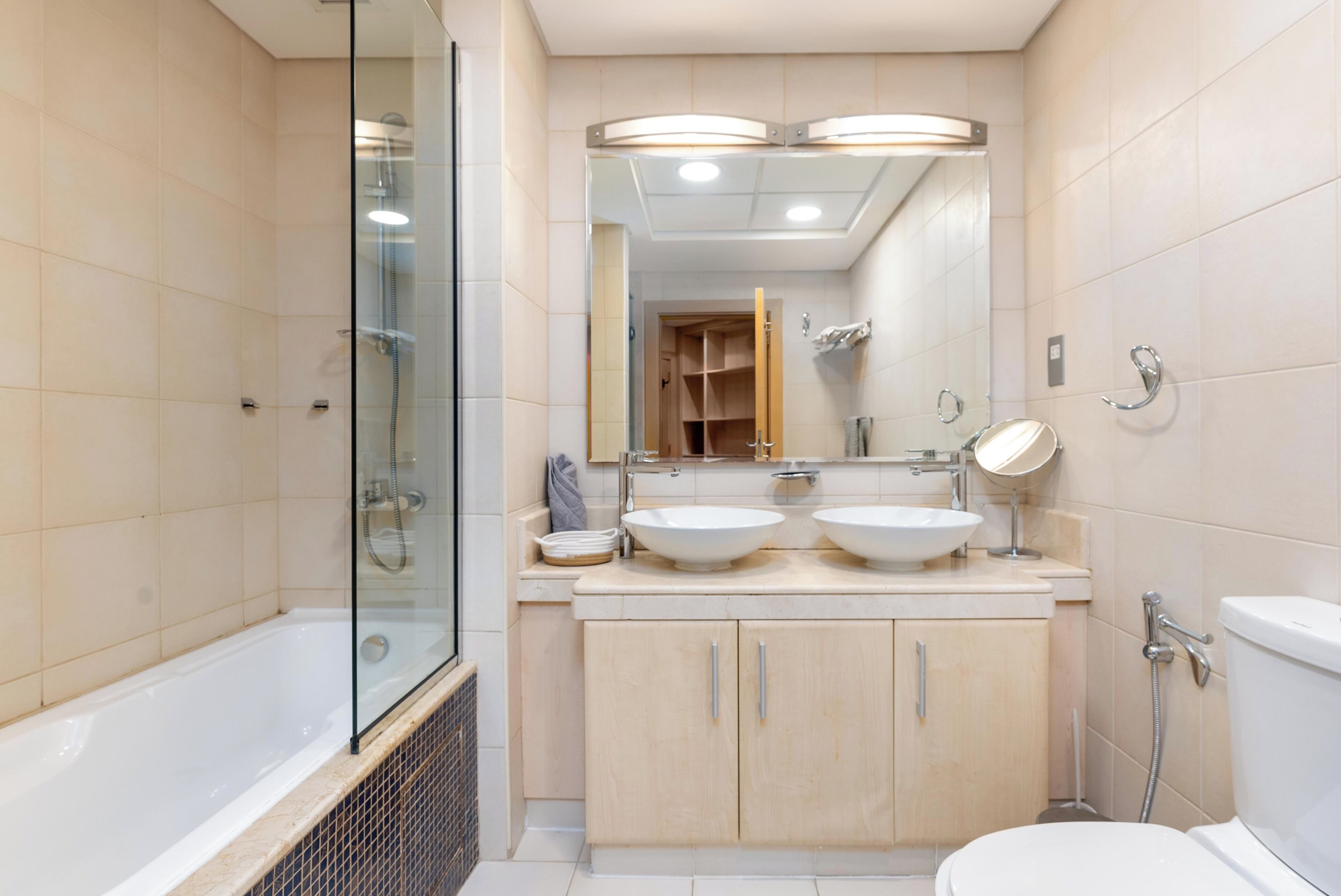 Een moderne badkamer met een douchecabine van glas, een wastafel met dubbele wasbak en een toilet.
