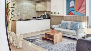 A modern living room with a grey sofa, wooden coffee table, and a patterned rug. - Cozy Golfside Studio (Abu Dhabi)