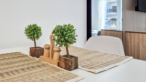 A table with two potted plants, a wooden mushroom-shaped planter, and woven placemats. - Cozy Golfside Studio (Abu Dhabi)