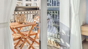 A balcony with a wooden table and chairs, a metal railing, and a view of buildings in the background. - Cozy Golfside Studio (Abu Dhabi)