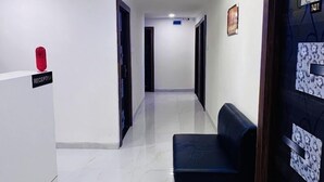 Een hotel receptie met een receptiebalie, een wachtruimte met een bank, en een gang naar andere kamers.