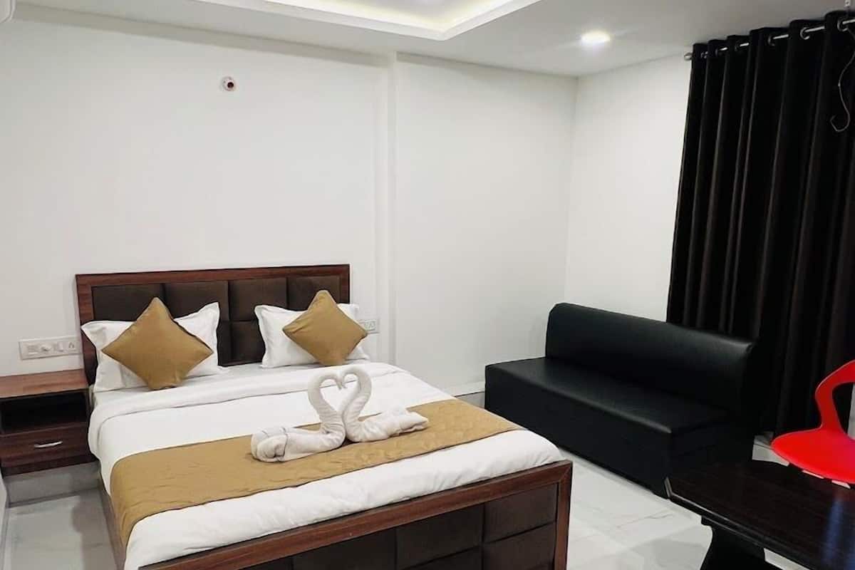 Una habitación de hotel moderna con una cama grande, un sofá negro y una silla roja.