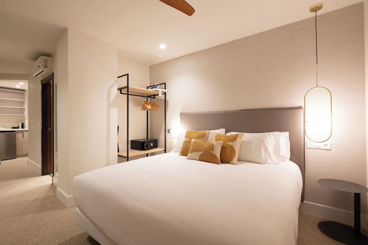 Une chambre d’hôtel moderne dotée d’un grand lit, d’une table de chevet, d’une lampe fixée au mur et d’un bureau intégré avec une chaise.