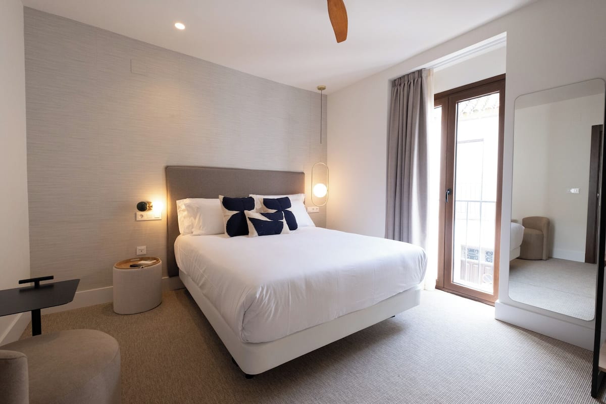 Une chambre d’hôtel moderne dotée d’un grand lit, d’un bureau, d’une chaise et d’un balcon avec vue.