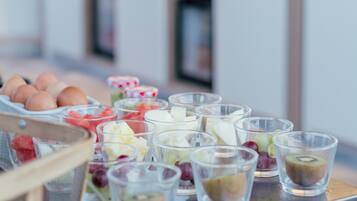 Een dienblad met diverse etenswaren, waaronder eieren, yoghurt en fruit.