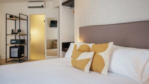 A hotel room with a large bed, a headboard, and a built-in shelf unit. - Hotel Cetina Casa de Aguilar (Córdoba)