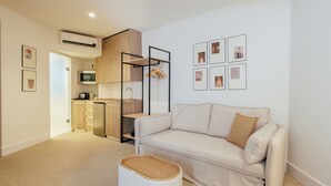 A modern living room with a sofa, a small table, and a kitchen area in the background. - Hotel Cetina Casa de Aguilar (Córdoba)