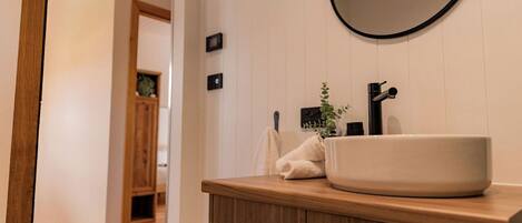 Une salle de bain avec un meuble-lavabo en bois, un miroir rond et un lavabo blanc.