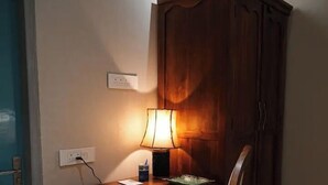 Una scrivania in legno con una lampada, una sedia e un armadietto in un angolo della stanza.