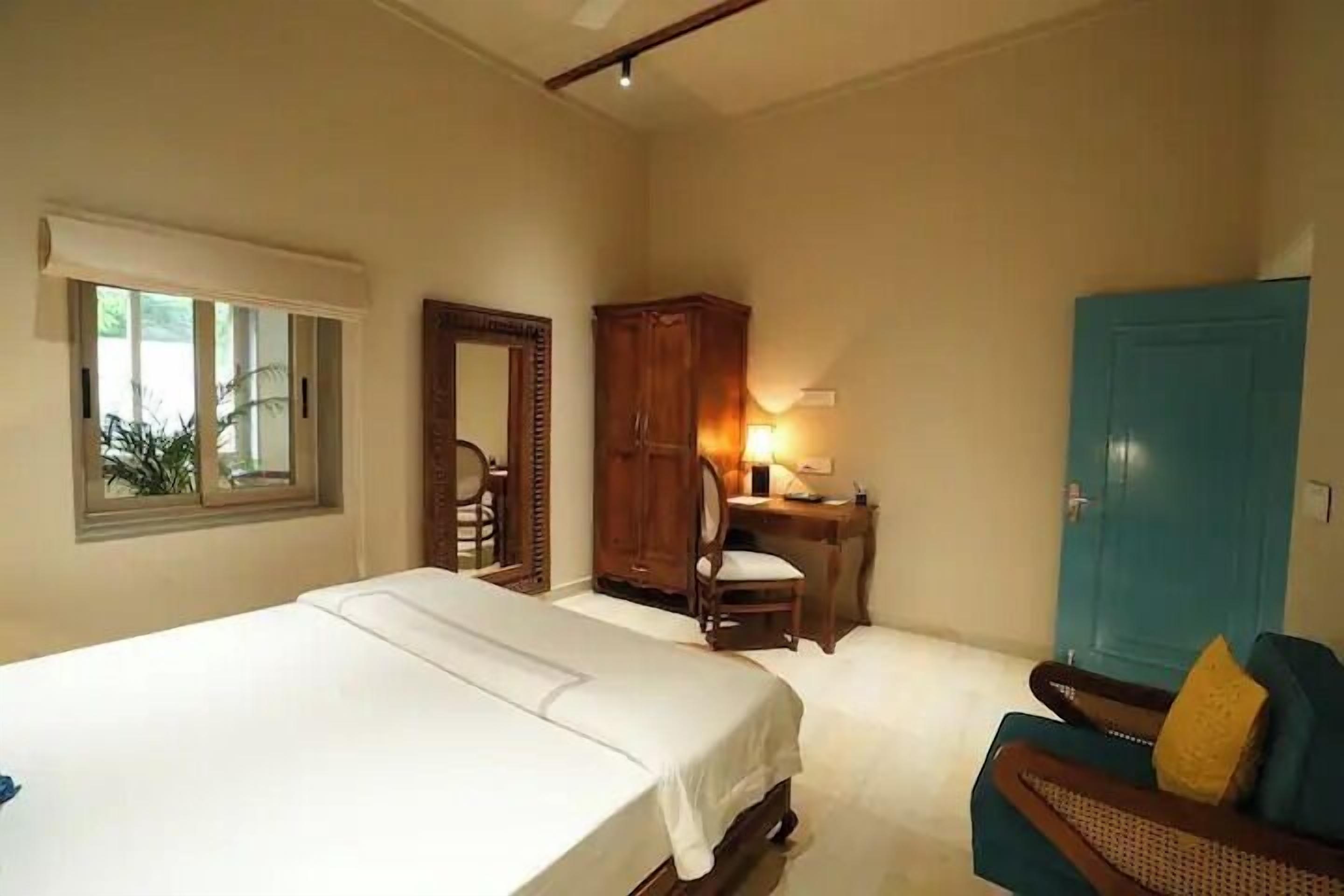 A bedroom with a bed, a desk, a chair, a wardrobe, and a door.