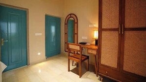 Una stanza con una scrivania in legno, una sedia, uno specchio e una porta blu.