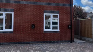 A two-story brick building with white-framed windows, a paved driveway, and a wooden fence. - 2 Bed Flat - Sleeps 4 - Pets - Garden - Parking (Nottingham)