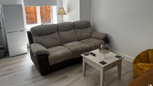 A living room with a grey sofa, a small table with a glass, and a yellow bean bag. - 2 Bed Flat - Sleeps 4 - Pets - Garden - Parking (Nottingham)