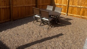 A wooden fence enclosing a patio area with a table and chairs. - 2 Bed Flat - Sleeps 4 - Pets - Garden - Parking (Nottingham)