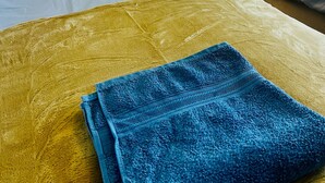 Ein Hotelzimmer mit zwei Betten, jeweils mit Kopfstütze, gelbem Kissen und einer Lampe auf dem Nachttisch.