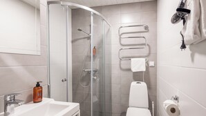 A modern bathroom with a glass shower enclosure, a white sink, and a toilet. - Frans&Frans hotel and apartments (Rauma)